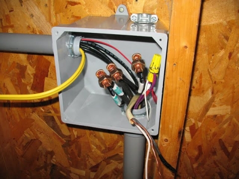 The junction box where the power and signal wires join the conduit heading to the back wall of the shed.